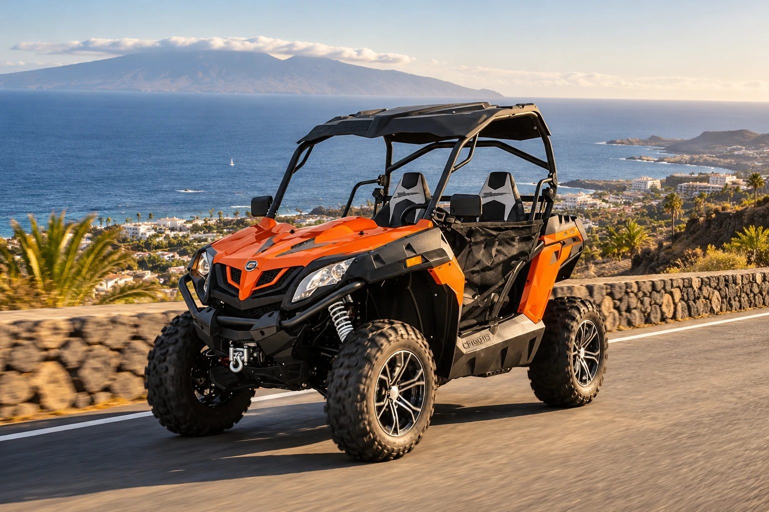 An orange buggy on the road above the coast, with the sea and La Gomera behind