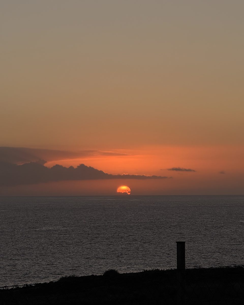 The sun touching the horizon over the sea, seen from the coast of Adeje
